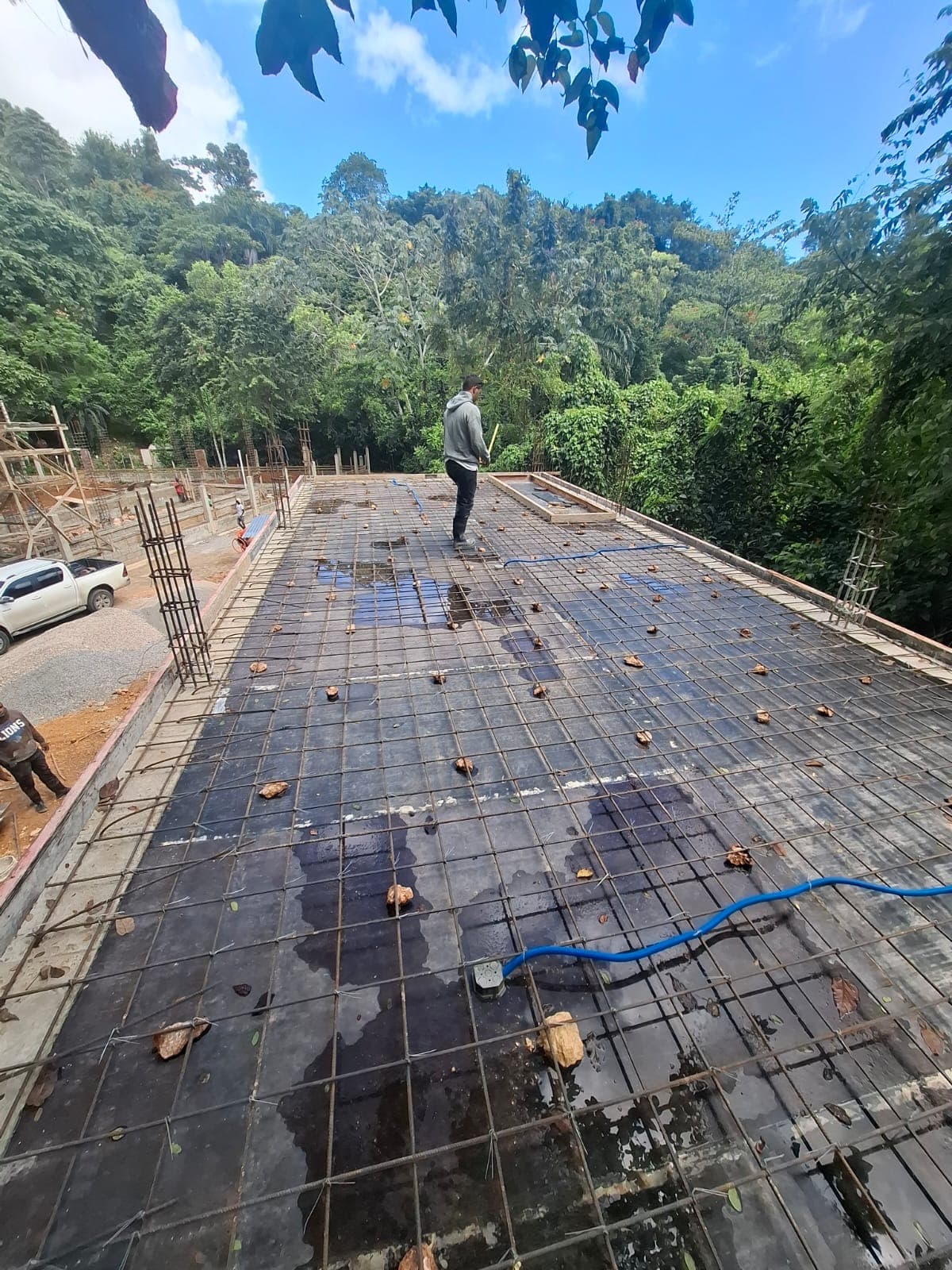 The poured upper slab with reinforcing steel laid out, jungle and hillside surrounding it